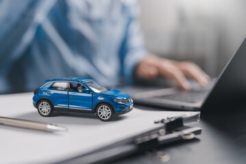 Car insurance and loan approval concept. A miniature car placed on insurance contract document policy agreement. vehicle finance, policy management, rental, sales, and claims service. © Anon