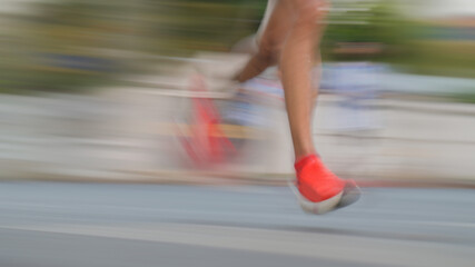 Naklejka premium Speed and energy: Blurred legs of athletes running on a street