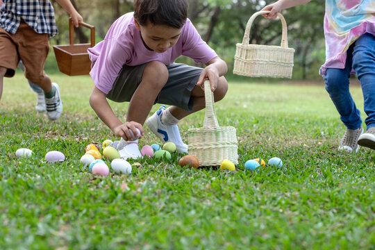 The children are having fun on an Easter egg hunt in the lawn. boy and girl bent down to pick up the Easter eggs and put them in their baskets. Children and Easter.