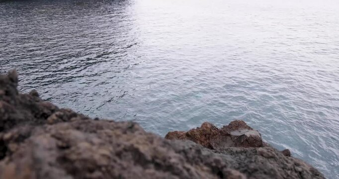 Steep volcanic cliffs by the Atlantic ocean rising from blue water at Capelas, Azores.