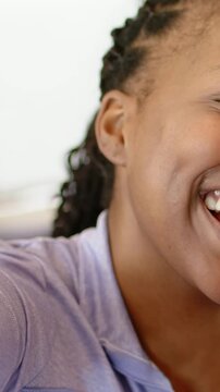 Vertical video: Pulling back camera revealing woman laughing on sofa sharing joy, in purple zip-up