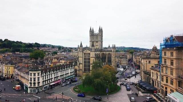 Cinematic aerial drone shot revealing Bath Abbey and surrounding streets in the historic city of Bath Somerset England with traffic and pedestrians