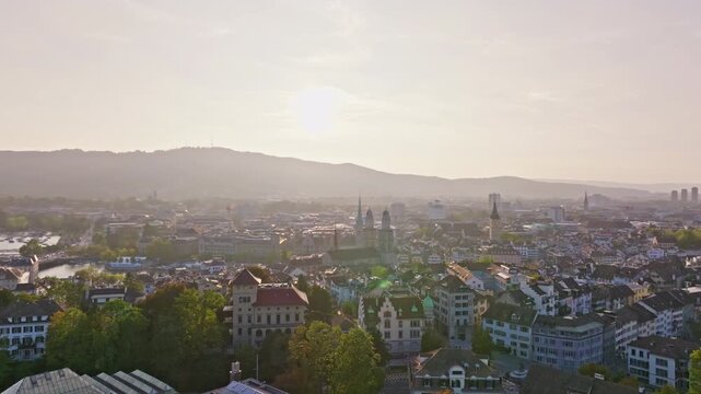 Smooth circular drone shot orbiting the Grossm&uuml;nster in Zurich with detailed views of the twin towers and surrounding Old Town. Iconic Swiss landmark, warm light, and cinematic urban atmosphere.