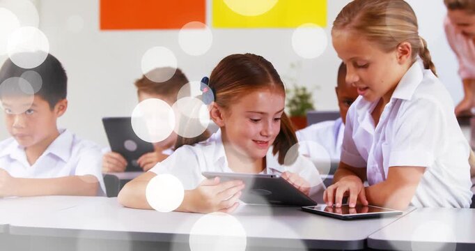 Seated girl glancing then tapping tablet, peer leaning pointing for learning, bokeh lights floating