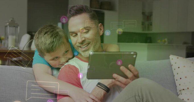 Dad and son sharing tablet in home, child climbing couch and causing floating social chat graphics