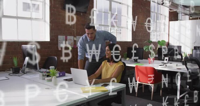 Male coworker leaning in woman typing on laptop as money icons drifting over laptop reviewing funds