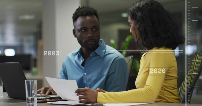 Woman showing sheet and man returning to laptop in office while reviewing page, timeline drifting