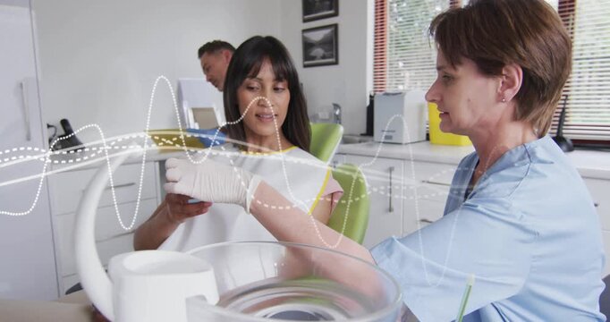 Clinician reaching in, adjusting patient bib and placing cup while waveform guiding dental prep