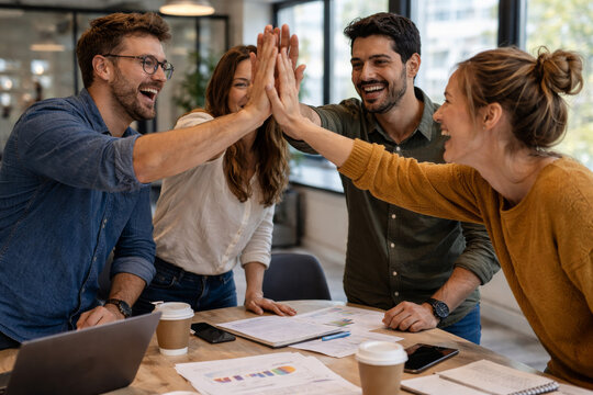 Happy business team celebrating success with high five in office