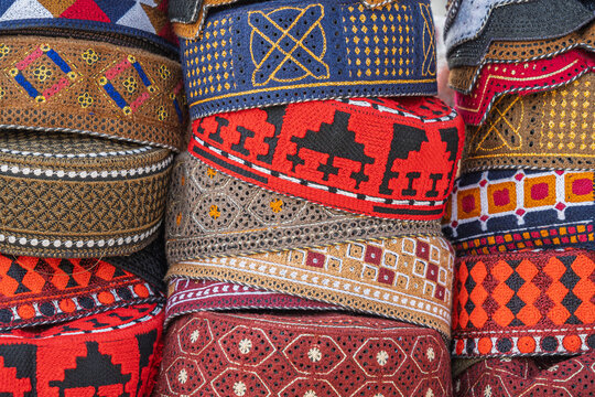 Closeup view of colorful traditional skull caps aka topi with embroidery design on outdoor stall in Pakistan