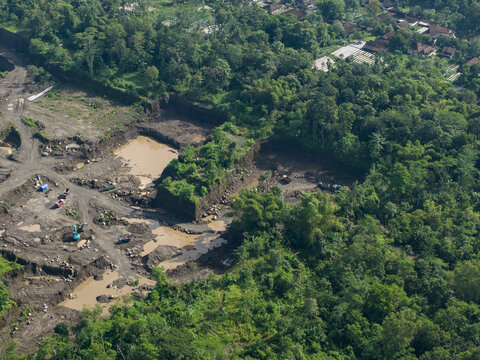 Aerial view of earthmoving machinery carving into the landscape amidst the lush greenery, Kali woro, Klaten Regency, Jawa Tengah, Indonesia.