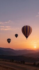 Obraz premium Hot Air Balloons Silhouetted Against a Colorful Sunset in the Mountains