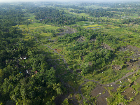 Aerial view of lush green vegetation interspersed with rugged terrain and pathways, creating a dynamic landscape, Klaten Regency, Jawa Tengah, Indonesia.