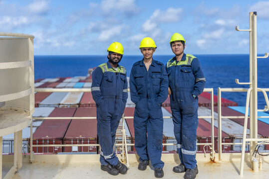 Maritime professionals standing on the upper deck near satellite equipment, taking a brief pause while at sea.