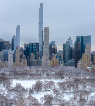 Aerial view of snow-dusted trees and skyscrapers, including Central Park Tower and 111 West 57th Street, under a winter sky, Manhattan, New York, United States.