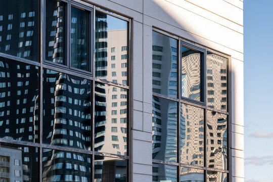 Modern corporate architecture building exterior with glass facade and reflection in a cityscape showing windows and urban skyline for business use