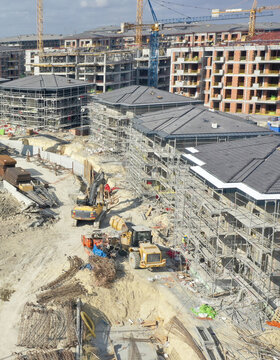 Aerial view of construction site with heavy machinery amidst unfinished buildings, framed by towering cranes against the sky, Avcilar, Istanbul, Turkey.