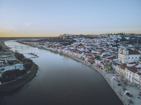 Aerial view of the Sado River reflecting the soft light of the setting sun as it meanders past the white-washed buildings, Alcacer do Sal, Setubal, Portugal.