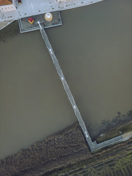 Aerial view of a modern footbridge stretching across the muddy waters of the Sado River, connecting the town, Alcacer do Sal, Setubal, Portugal.