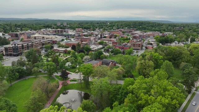 Aerial drone view over Saratoga Springs downtown with surrounding lake and lush trees in New York, United States &ndash; 24 June 2026 &ndash; scenic small city landscape under clear summer sky cinematic 4K.