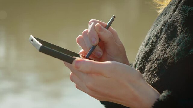 Mobile banking transaction processing through smartphone and stylus over wireless network. Unrecognizable woman managing online finance and transferring funds via secure digital application