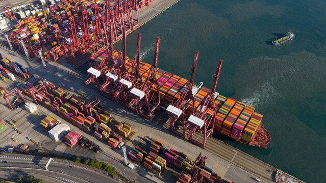 Aerial view of vibrant, stacked containers creating a colorful mosaic at the bustling Hong Kong port, framed by towering red cranes, Hong Kong, China.