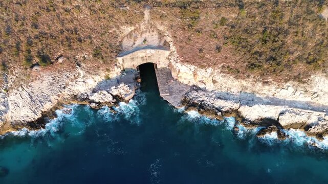 Aerial Top Perspective View Waves Crashing on Rocks near Submarine Bunker in Albania