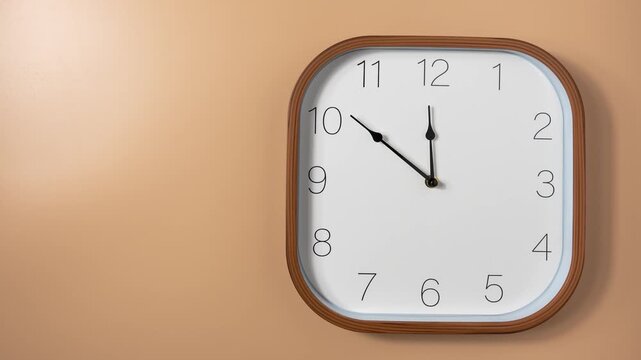 Minimalist wall clock on a beige wall with moving hands in timelapse. Concept of time passing, schedule, productivity, and daily routine.