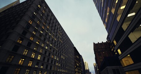 Naklejka premium predawn urban avenue with early office lights and muted sky, towering facades framing empty road, contrast between lit interiors and cool exterior tones, quiet
