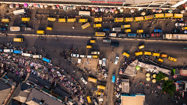 Lagos, Nigeria - 24 February 2026: Aerial view of a vibrant tapestry of yellow buses and bustling crowds converging near the Oshodi pedestrian overpass, a vivid scene of urban energy.