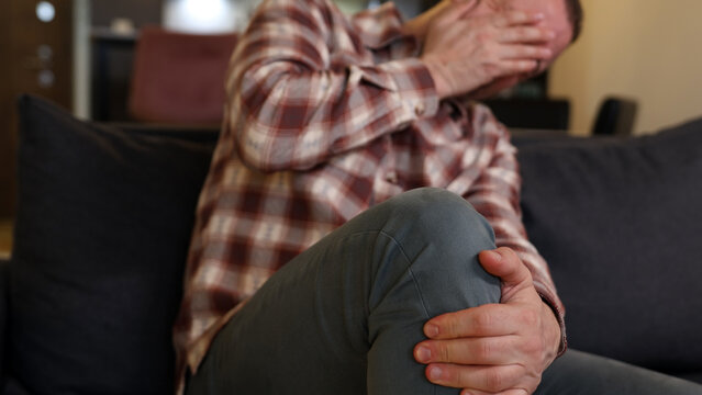 Man at home holding painful injured knee.