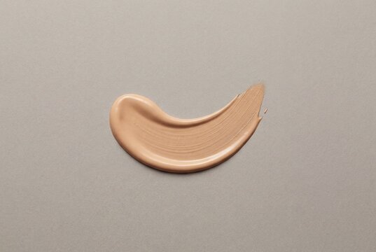 Liquid foundation makeup swatch smear on grey background with creamy beige texture for cosmetic use