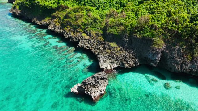 Medium cinematic aerial showing texture of cliffs and shallow reef below