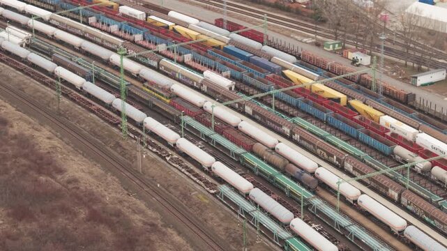 Aerial view of a large railway yard filled with freight trains, tanker wagons, and colorful cargo containers.