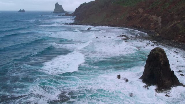 Dramatic aerial perspective of the wild Atlantic ocean shoreline. Powerful waves breaking against the volcanic cliffs of Anaga Rural Park. Tenerife, Canary Islands