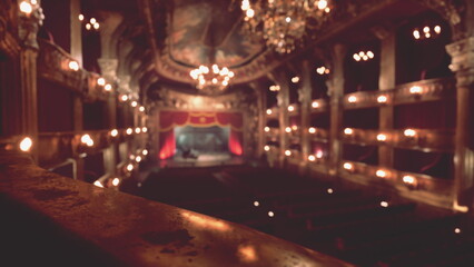 Naklejka premium Dim lights cast a warm glow on the grand theater interior, revealing ornate decorations and a stage prepared for a captivating performance. The atmosphere is alive with anticipation.