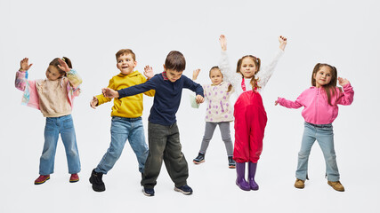 Children dancing wearing colorful mid season kids fashion outfits in studio. Concept of children clothing campaign, playful movement, seasonal apparel promotion and joyful childhood lifestyle.