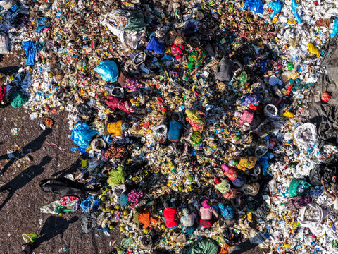 Chattogram, Bangladesh - 25 November 2025: Aerial view of Anondobazar Landfill reveals a stark tapestry of discarded clothing and waste, shadowed by figures scavenging amidst the colorful debris.