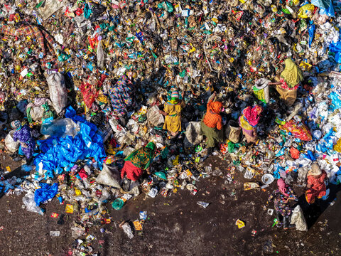 Chattogram, Bangladesh - 25 November 2025: Aerial view of Anondobazar Landfill, where vibrant colors of discarded materials contrast with the dark, damp ground, as figures sort through the debris.