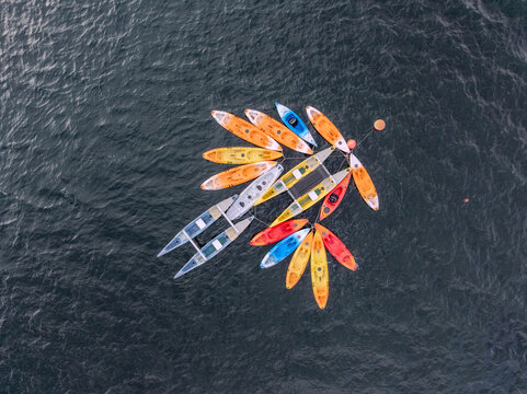 Aerial view of a kaleidoscope of kayaks, a vibrant mosaic on the dark water, their colorful hulls a striking contrast, Alqueirao, Braga, Portugal.
