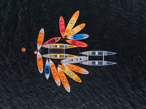 Aerial view of a cluster of colorful kayaks in a whimsical pattern floating on the water, Alqueirao, Braga, Portugal.
