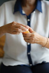 Elder female calmly taking medicine from bottle while sitting in home living room for wellness routine