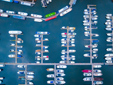 Aerial view of boats lined up neatly in a marina, their white hulls contrasting against the deep blue water, Reading, Berkshire, United Kingdom.
