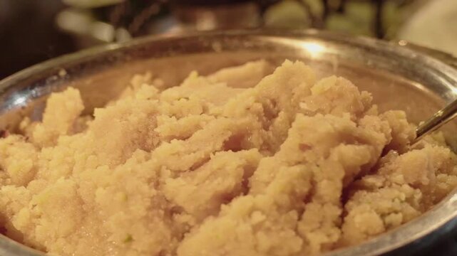 Close-up shot of freshly prepared suji ka halwa, a traditional Indian dessert made from semolina, ghee, and sugar. Hot sweet dish commonly served during festivals and religious occasions.