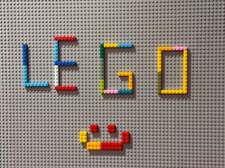 Fototapeta premium Lego letters and smiley on gray baseplate