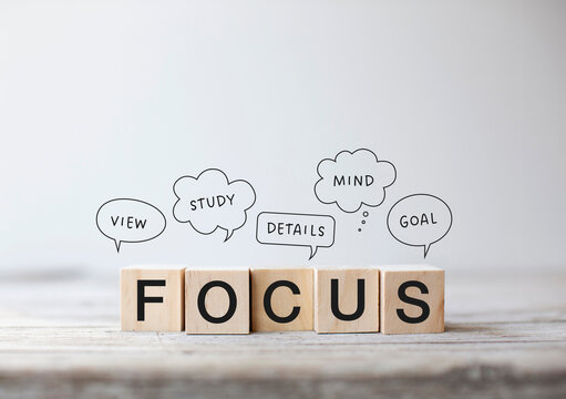 5 small wooden cubes with the word &ldquo;Focus&rdquo; written on them. Speech bubbles above them with the words: View, Study, Details, Mind, Goal