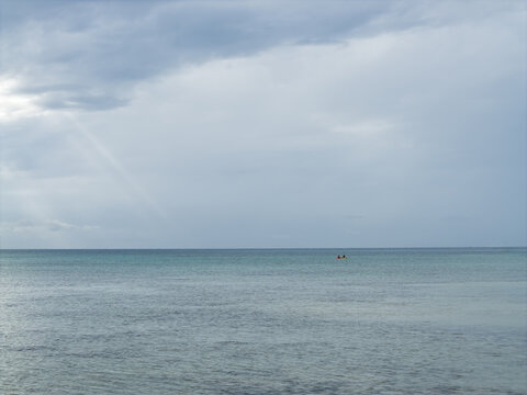 Aerial view of the tranquil sea stretches to the horizon under a sky streaked with soft blues and grays, Karimunjawa, Central Java, Indonesia.