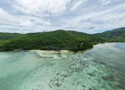 Aerial view of lush green island meeting the turquoise sea, Bobby Beach, Karimunjawa, Central Java, Indonesia.