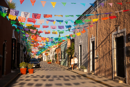 Colorful papel picado flags adorn a charming street in Valladolid, Mexico