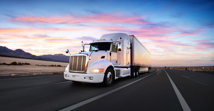 White semi truck / lorry and highway / road at sunset - transportation background. Beautiful sky and romatic feel. White body / side of the truck. Wide angle / panoramic view.